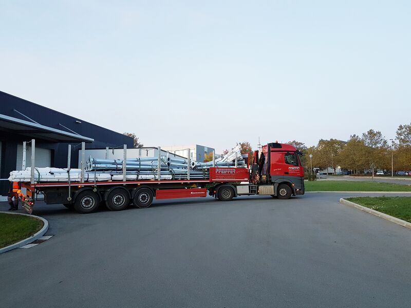Pfeiffer-LKW mit Ladekran, beladen mit feuerverzinkten Lichtmasten, bei der Anlieferung